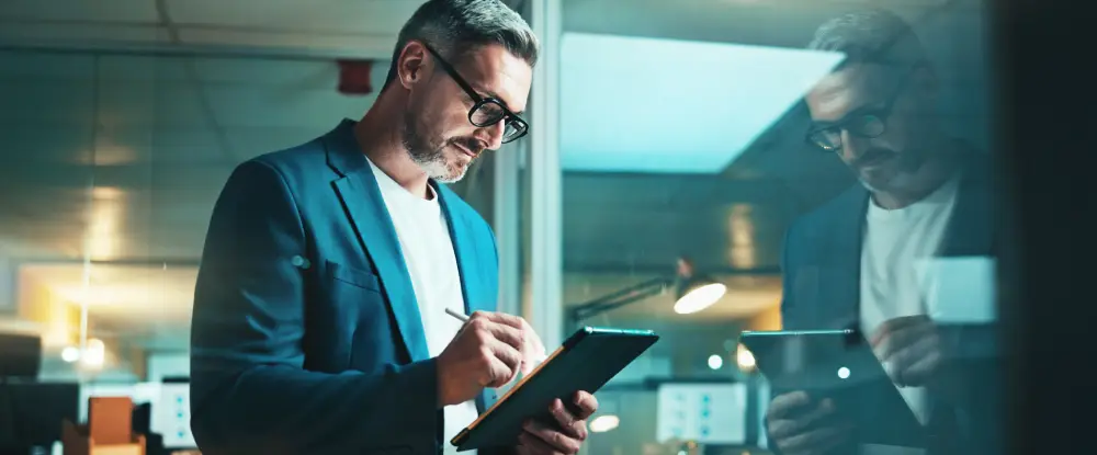 Een man in zakelijke kleding werkt geconcentreerd op een tablet.